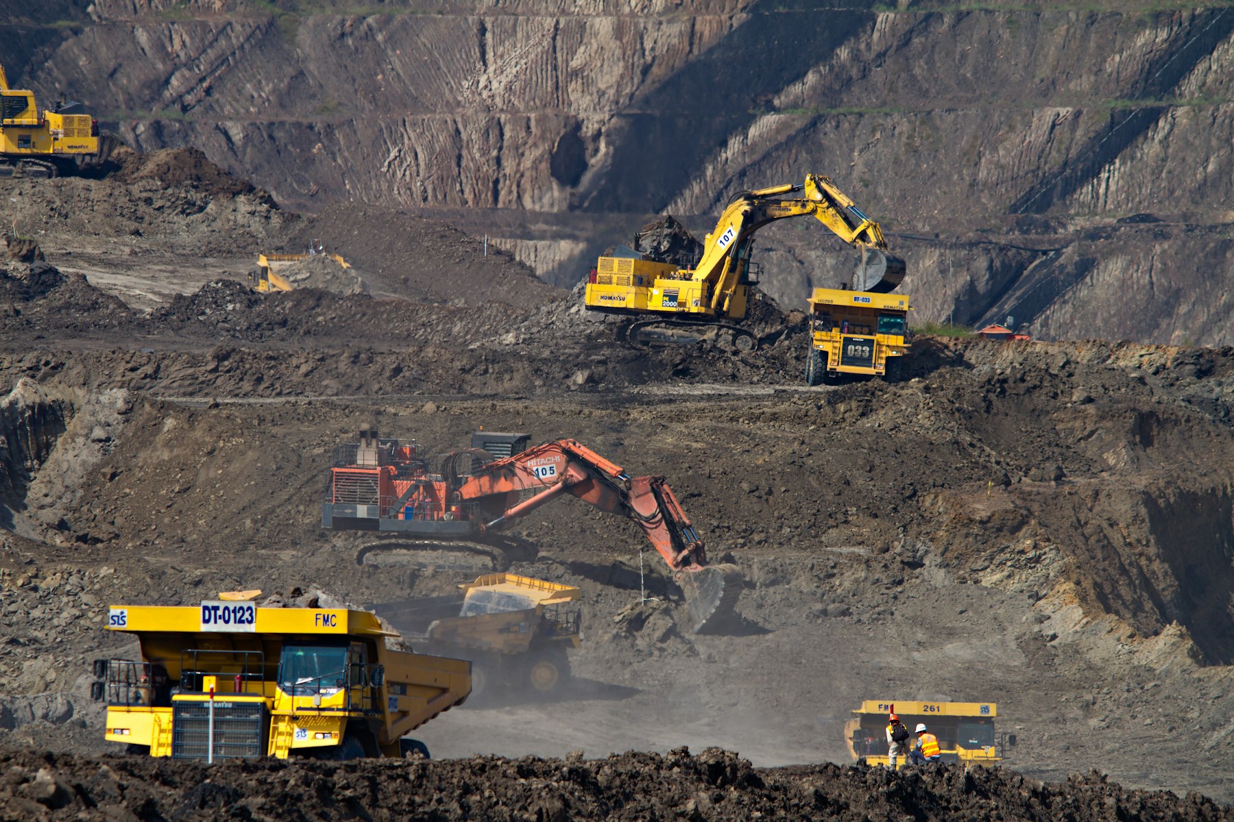 Excavators and haul trucks working the benches of an open-cut mine